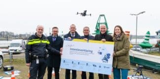 Drone2Go: de deelnemers met een vergrote versie van de intentieverklaring die zij getekend hebben. Buiten, met een drone boven hen.