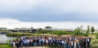 Het feestelijke overdrachtsmoment; feestgangers met op de achtergrond de nieuwe brug
