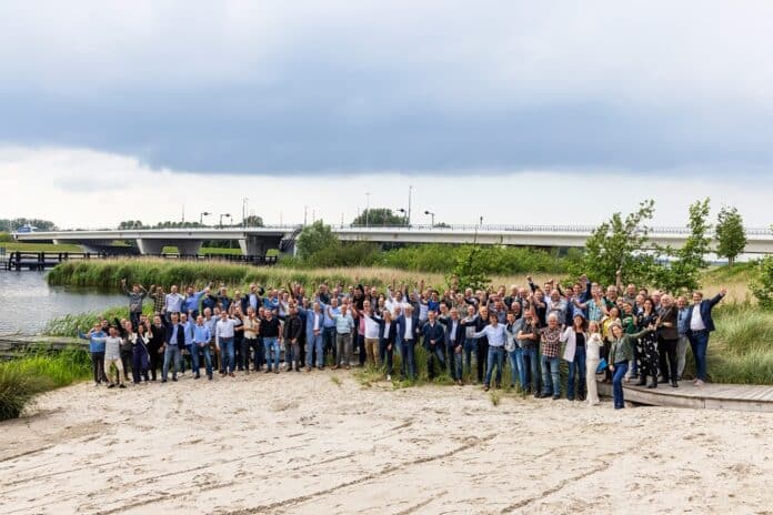 Het feestelijke overdrachtsmoment; feestgangers met op de achtergrond de nieuwe brug